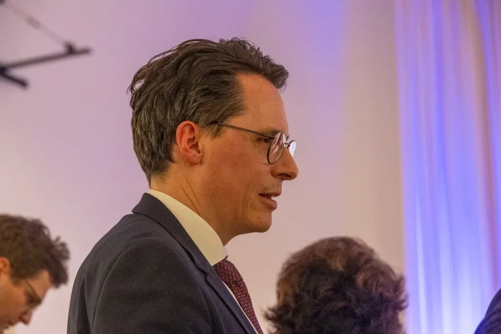 Mann mit Brille im dunklen Anzug im Gespräch bei einer festlichen Veranstaltung
