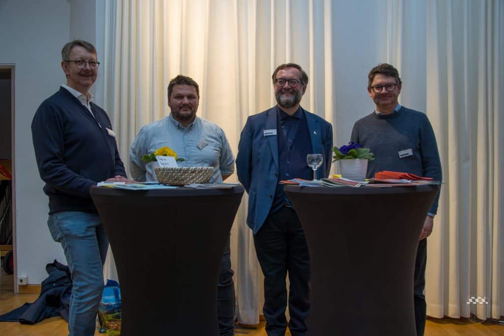 Vier Männer stehen an Tischen