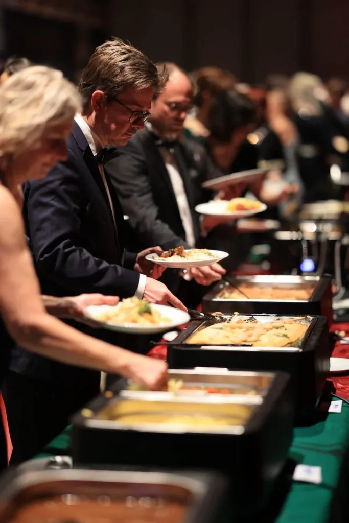 Gäste bedienen sich an einem Buffet mit verschiedenen Speisen.