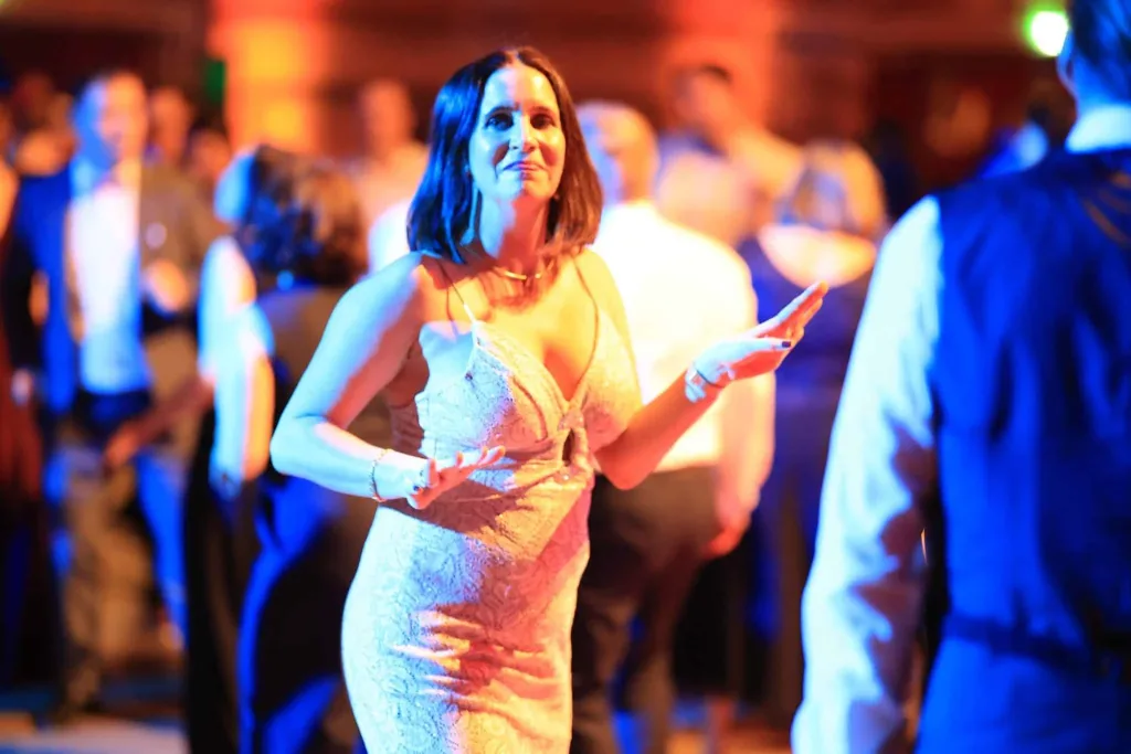 Tanzende Frau in einem hellen Abendkleid in einem stimmungsvoll beleuchteten Saal