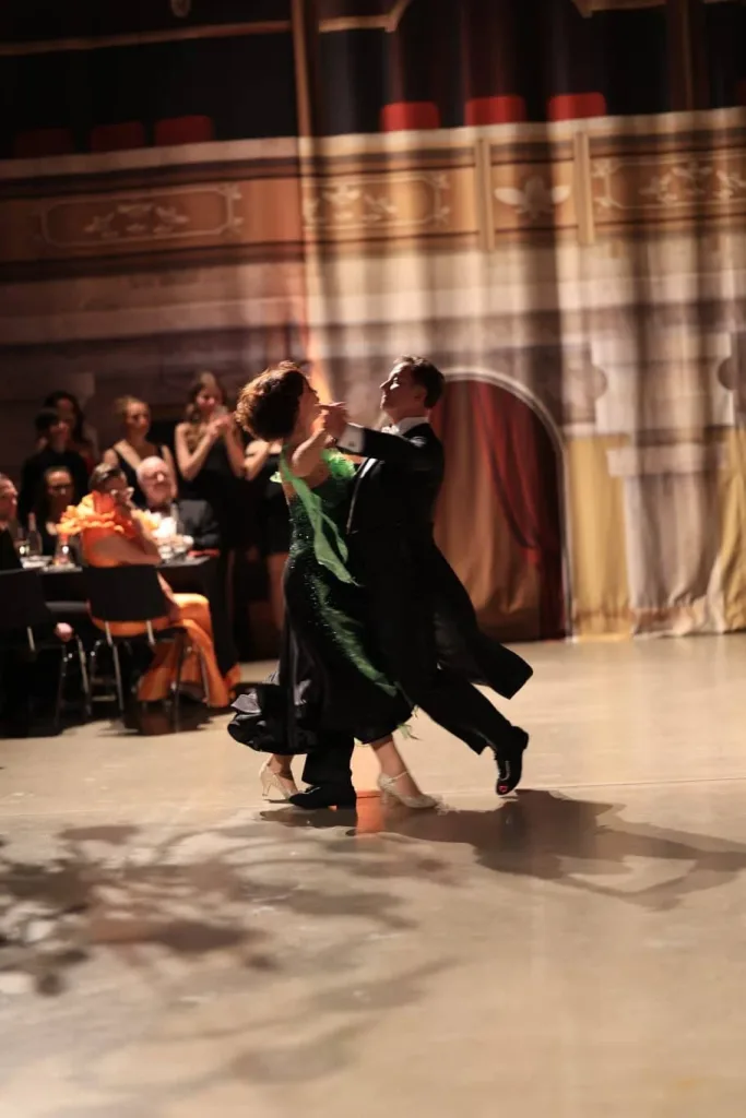 Ein elegant gekleidetes Paar tanzt im Ballsaal vor Publikum.