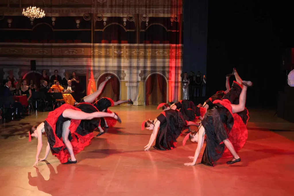 Tanzgruppe in roten und schwarzen Kostümen bei einer gemeinsamen Bühnenchoreografie